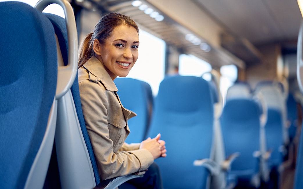 Young woman smiling while seated on a train journey.