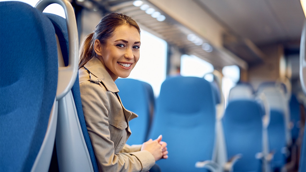 Woman seated inside a blue - seats bus smiling for the camera