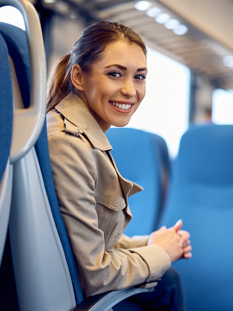 Young woman smiling while seated on a train journey.
