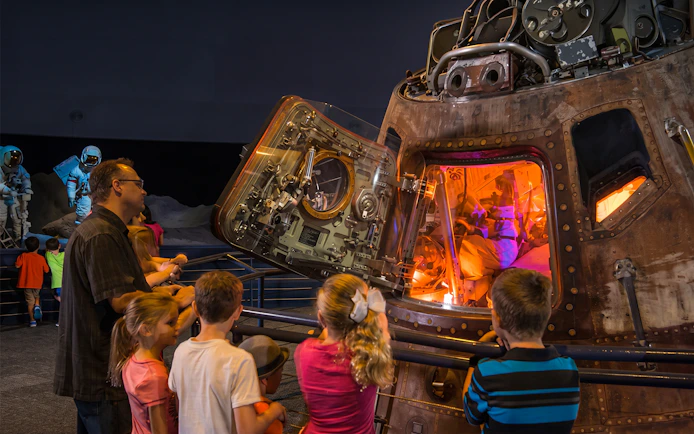 Visitors observing a space capsule exhibit at Space Center Houston.
