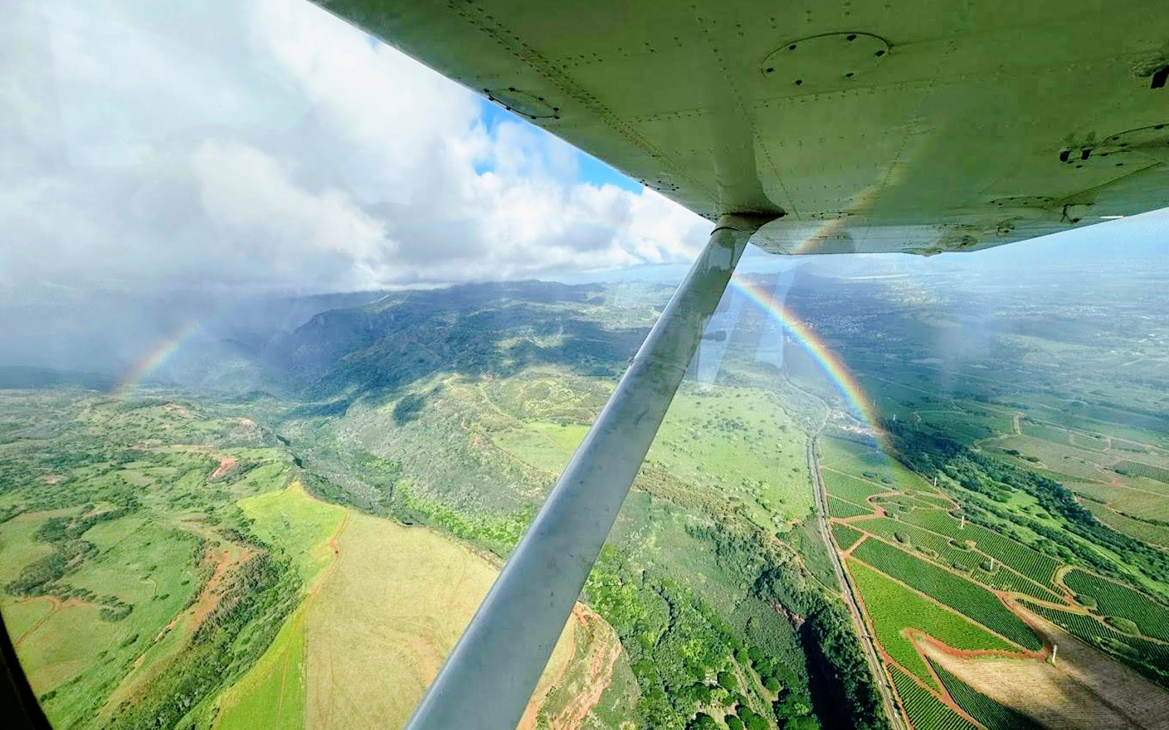Aerial view of Kauai landscape with rainbow seen from helicopter tour.