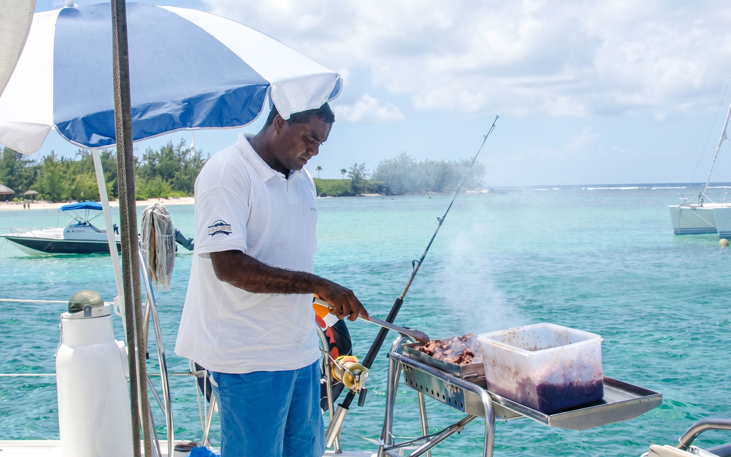Grilling on a catamaran near Ile aux Cerfs, Mauritius, with turquoise waters in the background.