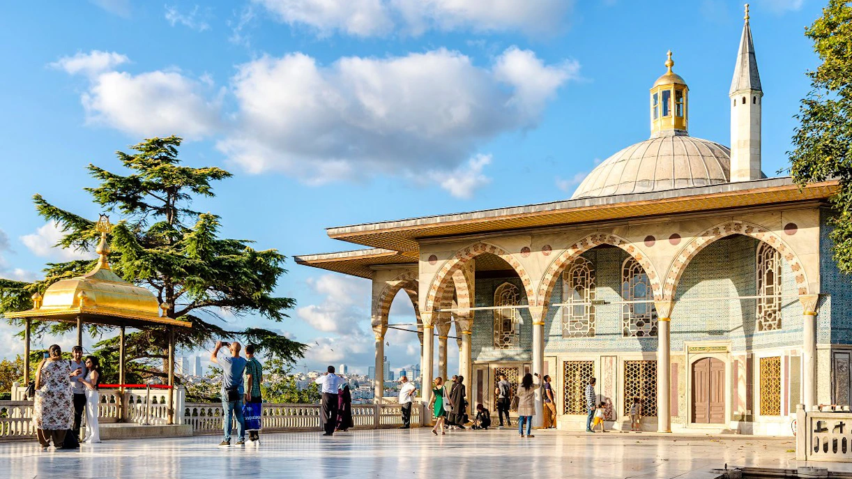 Topkapi Palace fourth courtyard with tourists exploring the pavilion and gardens.