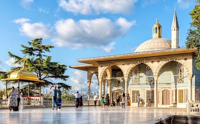 Topkapi Palace fourth courtyard with tourists exploring the pavilion and gardens.