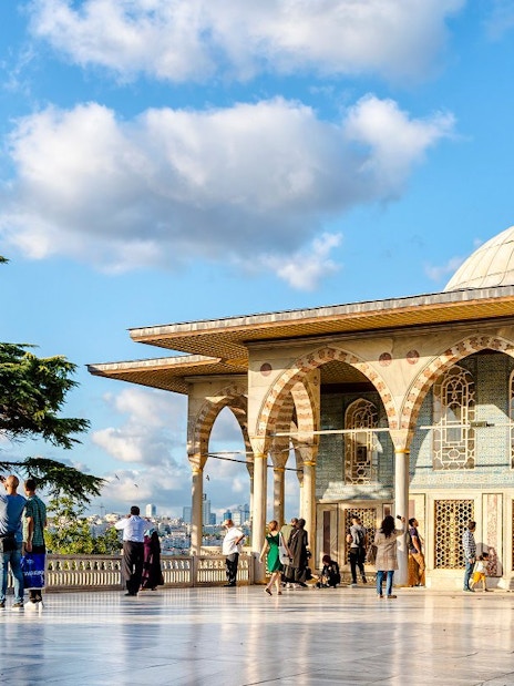 Topkapi Palace fourth courtyard with tourists exploring the pavilion and gardens.