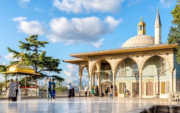 Topkapi Palace fourth courtyard with tourists exploring the pavilion and gardens.