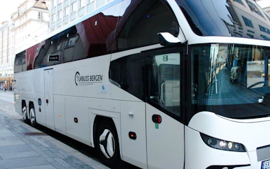 Bergen tour bus parked on city street for transfers.