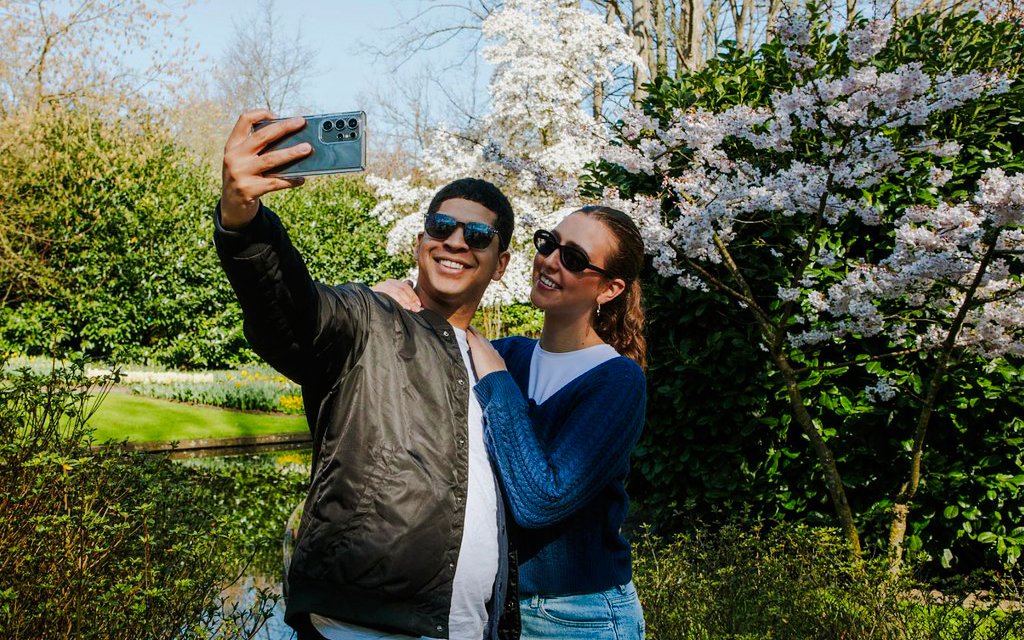 Visitors taking a selfie among blooming cherry blossoms at Keukenhof Gardens, Amsterdam.