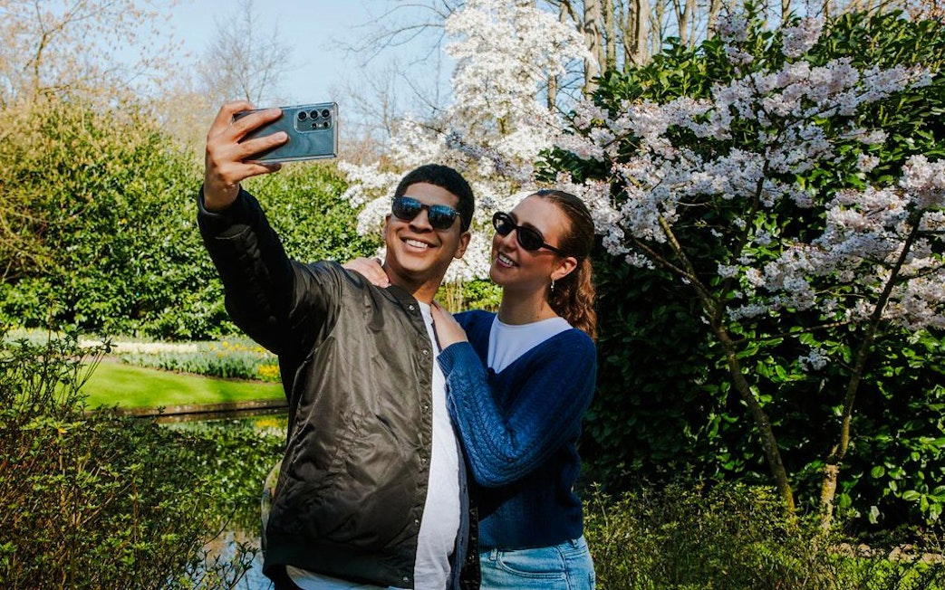 Visitors taking a selfie among blooming cherry blossoms at Keukenhof Gardens, Amsterdam.
