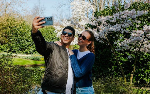 Visitors taking a selfie among blooming cherry blossoms at Keukenhof Gardens, Amsterdam.