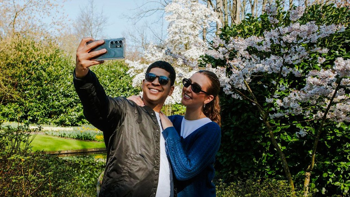 Visitors taking a selfie among blooming cherry blossoms at Keukenhof Gardens, Amsterdam.