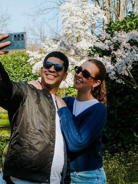 Visitors taking a selfie among blooming cherry blossoms at Keukenhof Gardens, Amsterdam.