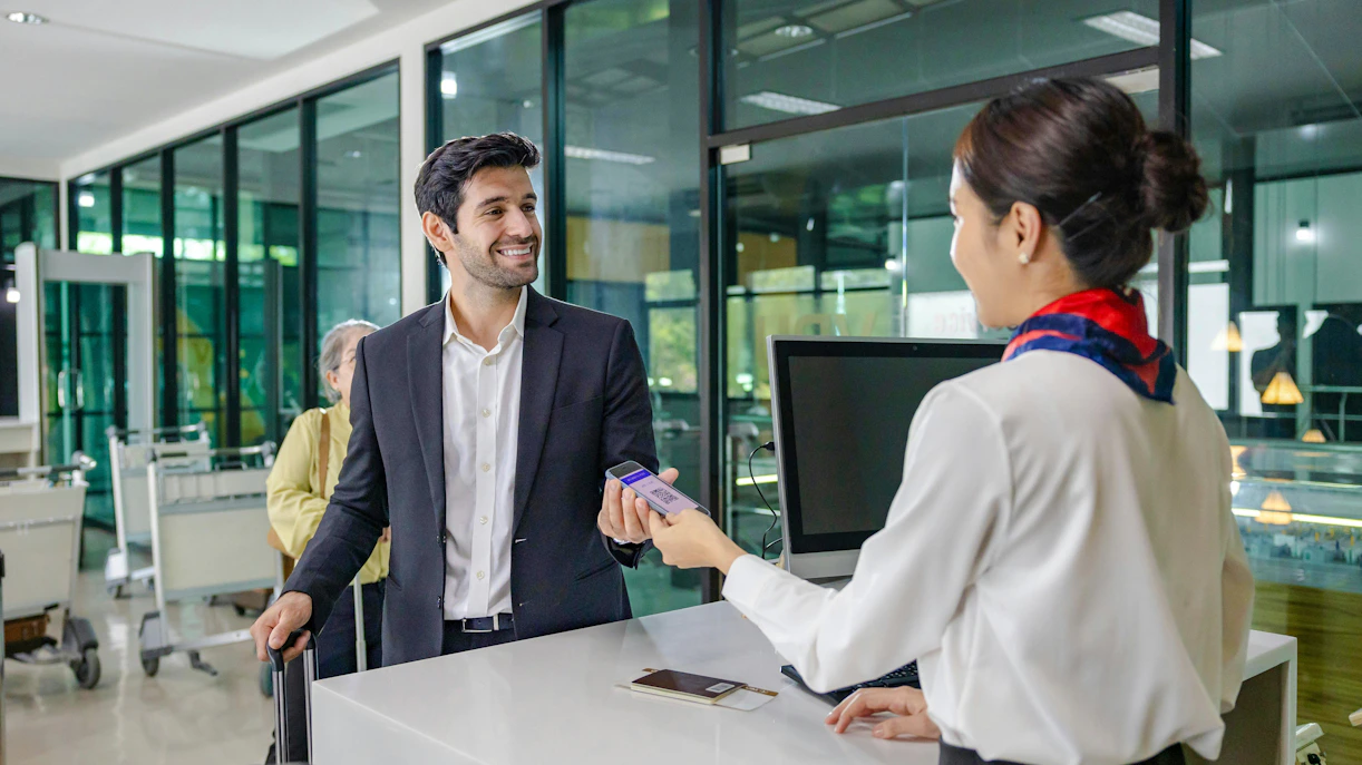 Man presenting digital boarding pass at airport check-in counter.