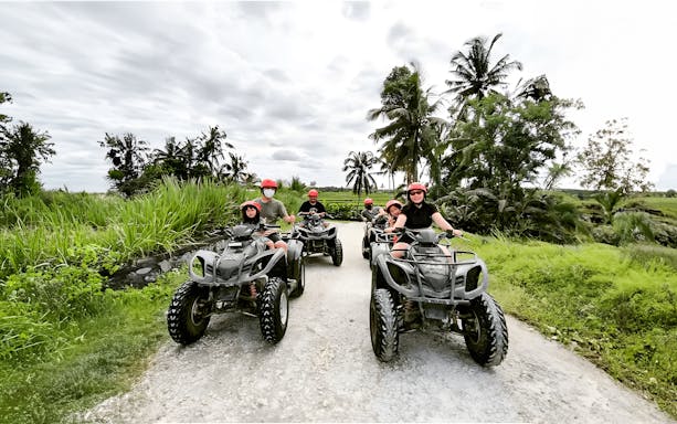 ATV riders on a dirt path surrounded by lush greenery in Ubud, Bali.
