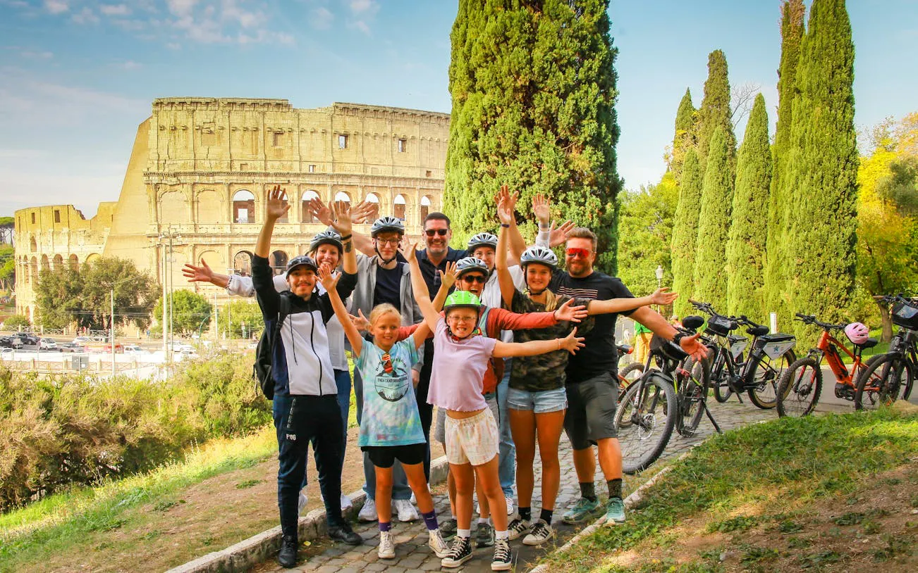 Group of cyclists posing with the Colosseum in Rome during a city bike tour.
