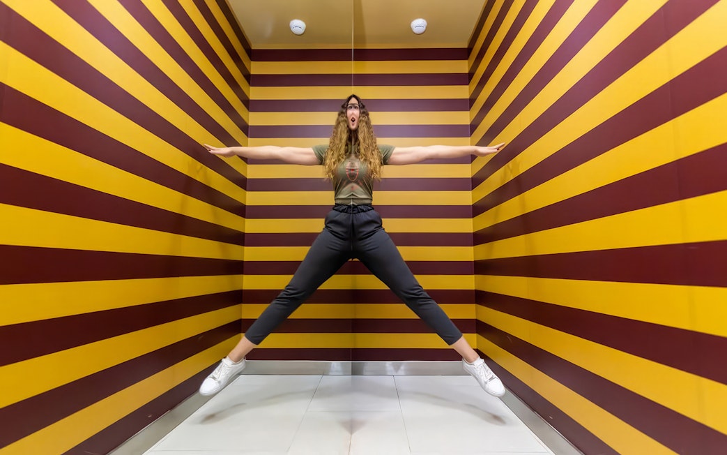 Person posing in an optical illusion room at Museum of Illusions Dubai.