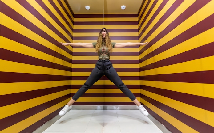 Person posing in an optical illusion room at Museum of Illusions Dubai.