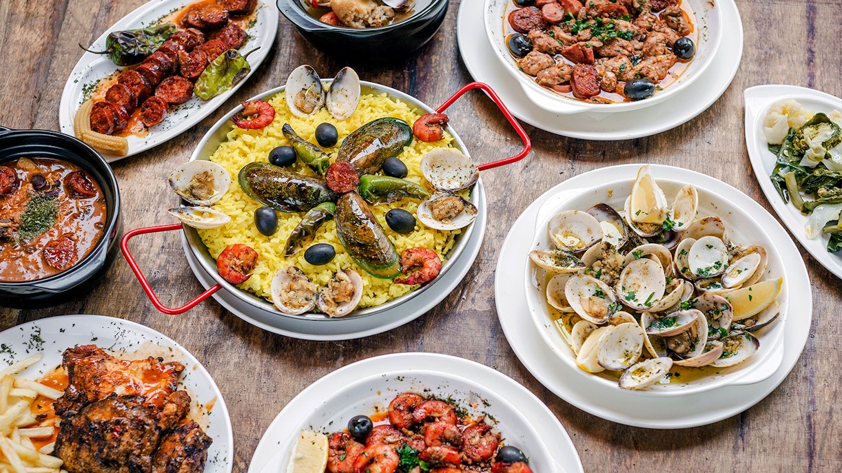 Portuguese rustic tapas with clams, chorizo, and rice on a wooden table.