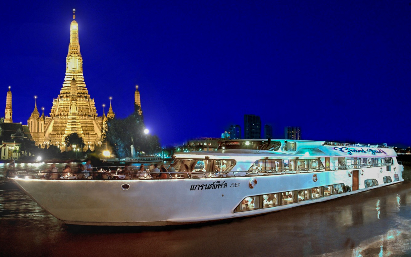Grand Pearl Dinner Cruise passing Wat Arun at night in Bangkok, Thailand.