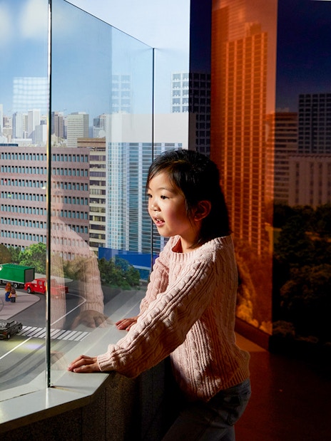 Child observing LEGO cityscape with Ferris wheel at LEGOLAND Discovery Centre.