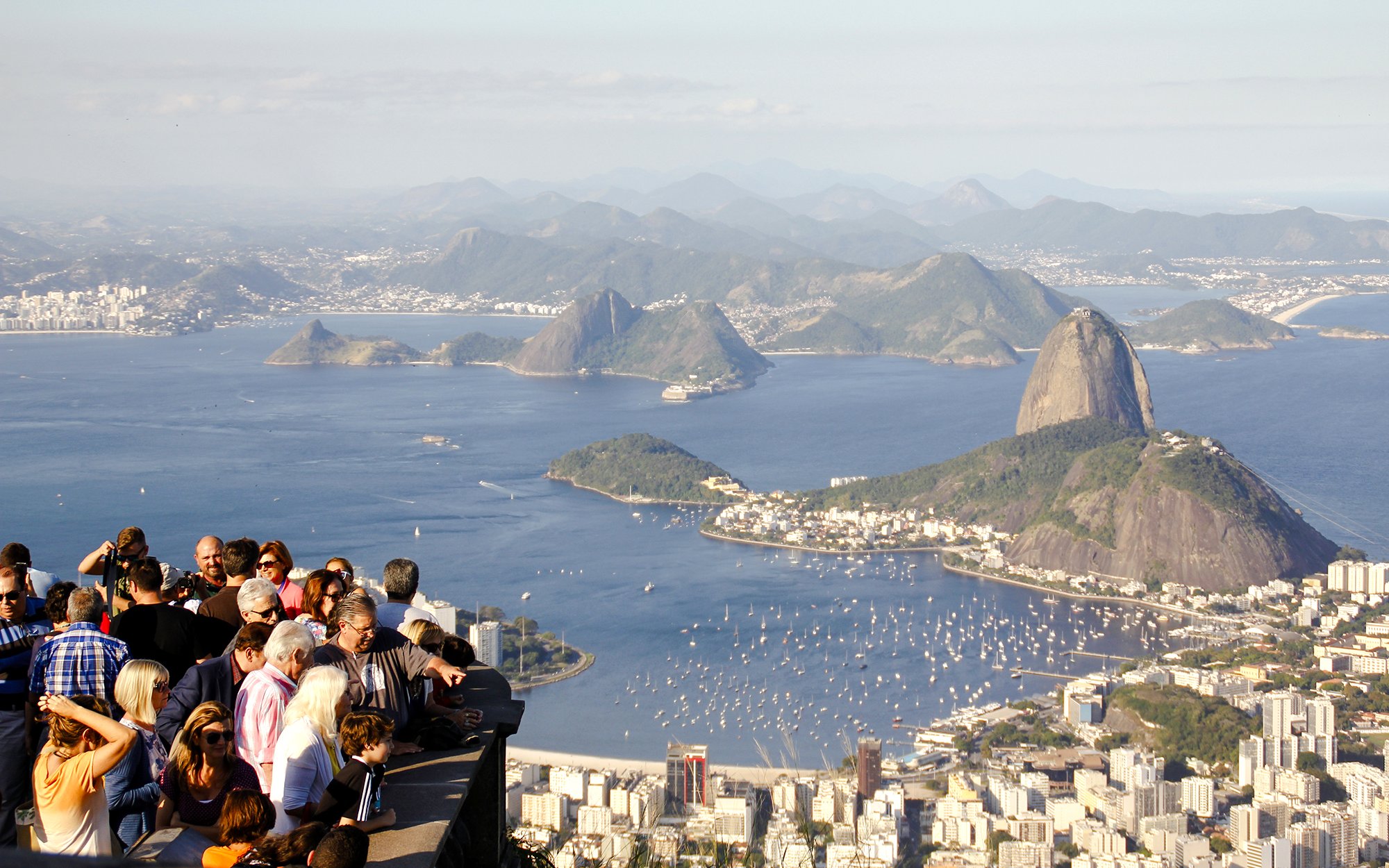 Crowd enjoying panoramic view of Rio de Janeiro from Christ the Redeemer viewpoint, with Sugarloaf Mountain.