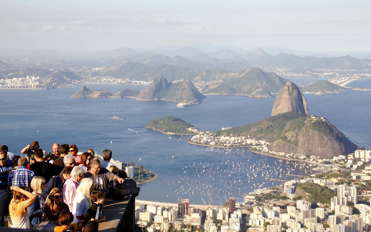 Crowd enjoying panoramic view of Rio de Janeiro from Christ the Redeemer viewpoint, with Sugarloaf Mountain.