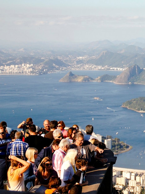 Crowd enjoying panoramic view of Rio de Janeiro from Christ the Redeemer viewpoint, with Sugarloaf Mountain.