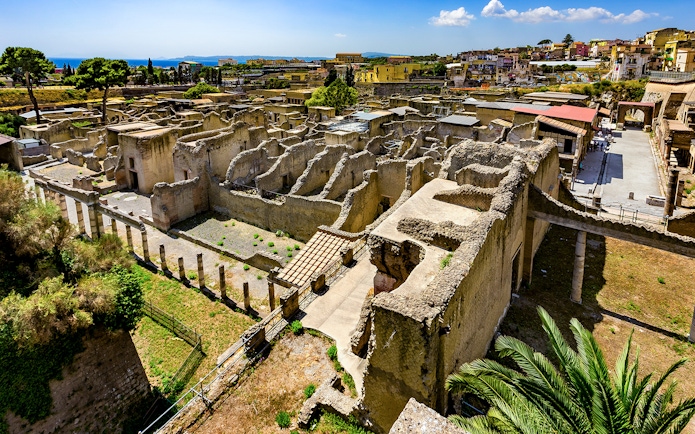 Aerial view of ancient ruins in Herculaneum, Italy, with surrounding landscape.