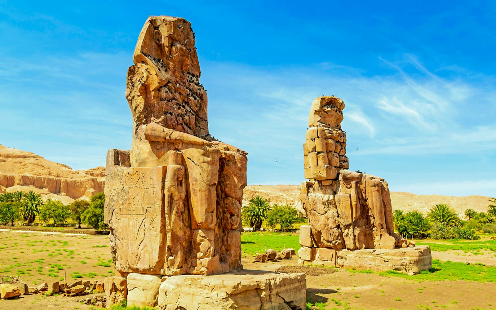 Colossi of Memnon statues in Luxor, Egypt, under a clear blue sky.