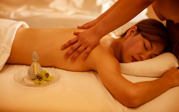 Person receiving a massage with Diora Signature Body Scrub nearby.