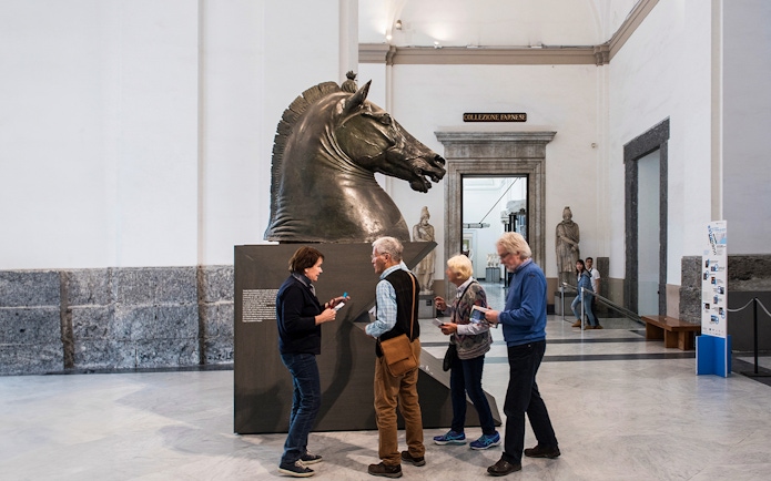 Visitors examining a horse sculpture at Naples National Archaeological Museum.