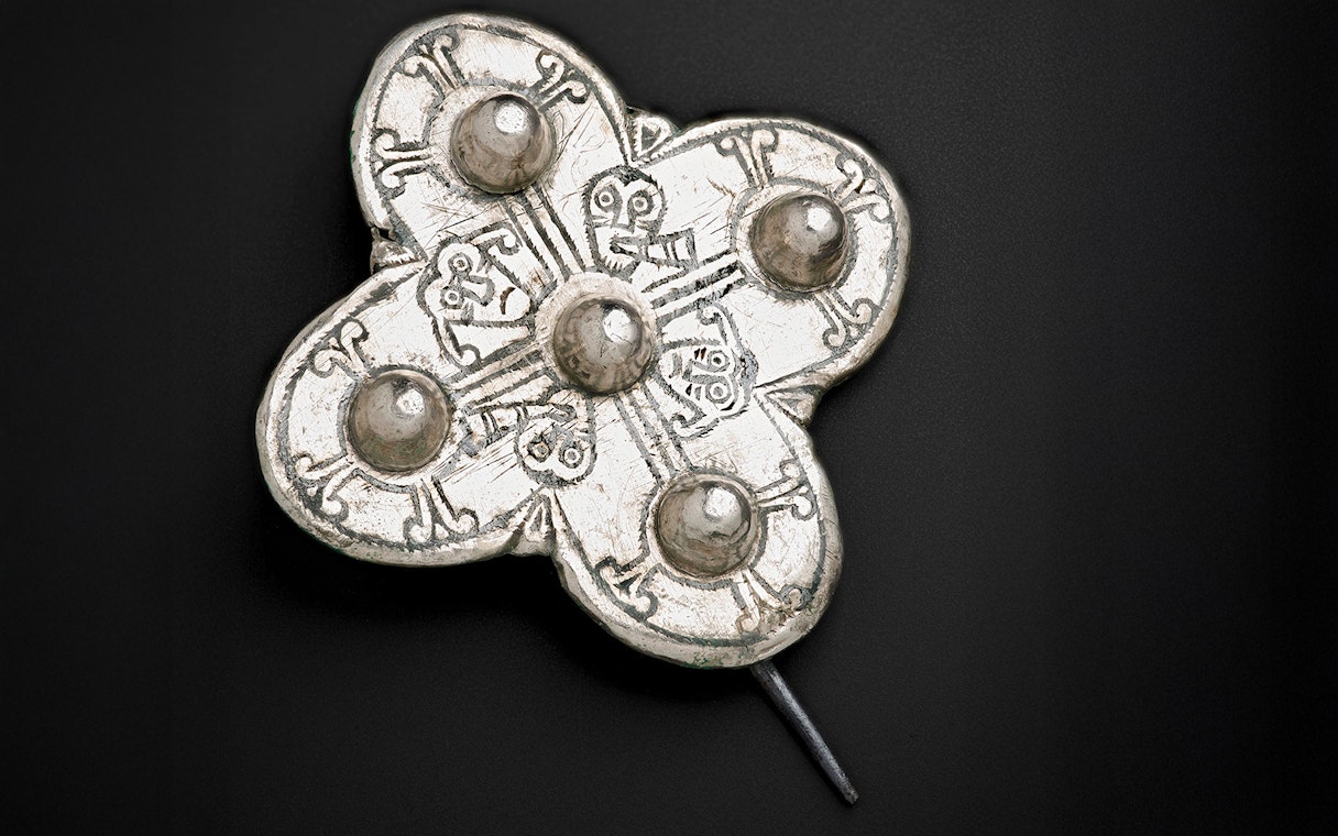 Viking Age brooch with intricate design and raised circular patterns.