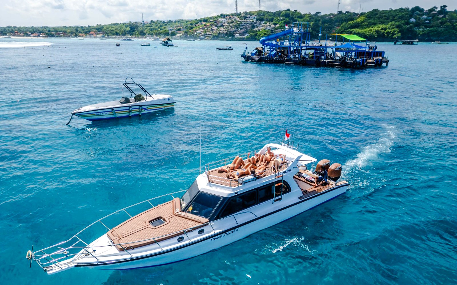 Boat tour with passengers relaxing on deck near West Nusa Penida Island.