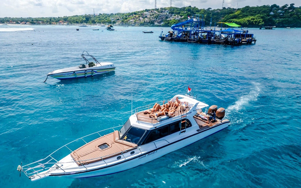 Boat tour with passengers relaxing on deck near West Nusa Penida Island.