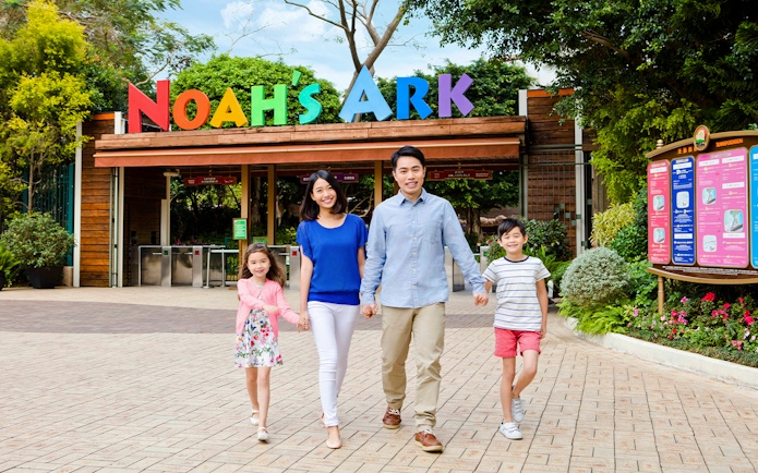 Family walking at Noah's Ark entrance, Hong Kong, with colorful sign above.