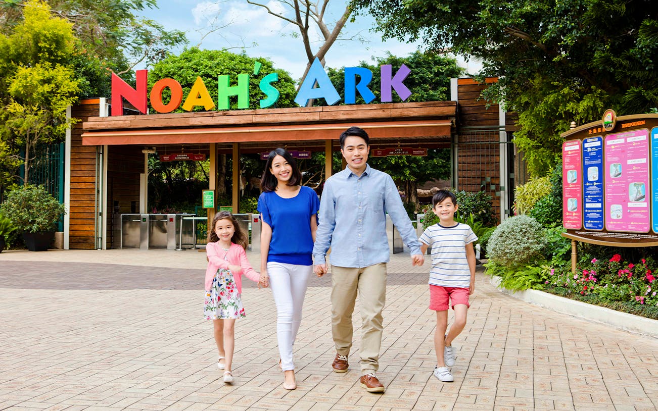 Family walking at Noah's Ark entrance, Hong Kong, with colorful sign above.
