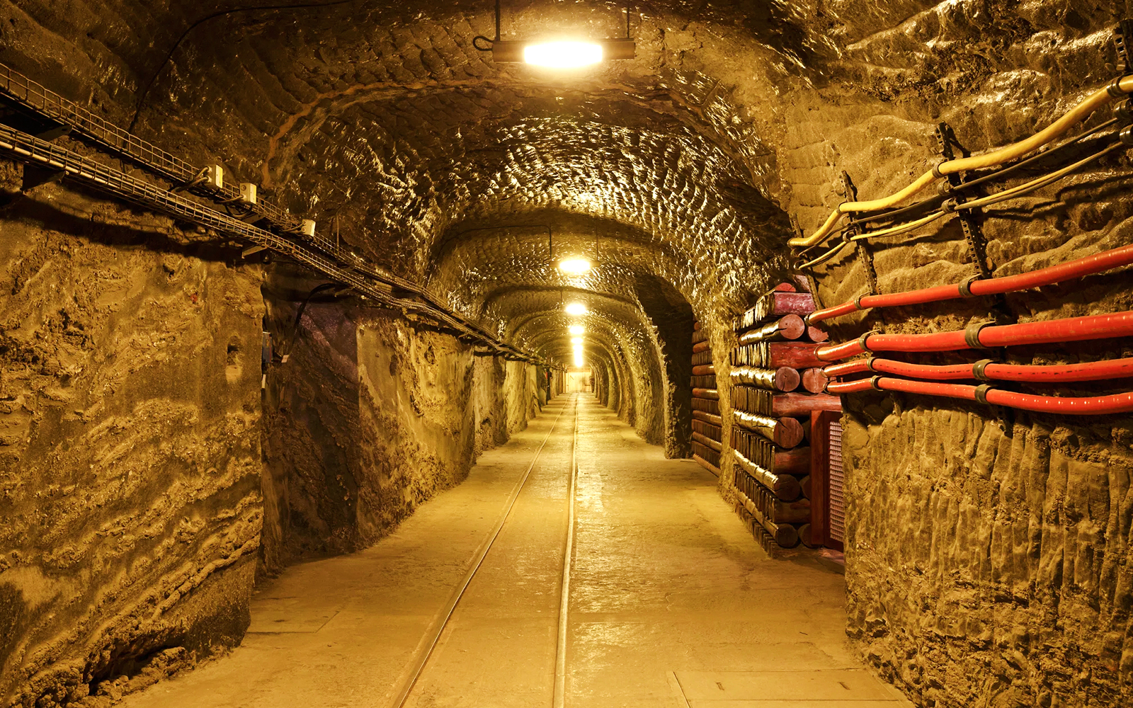 Wieliczka Salt Mine tunnel with illuminated arched ceiling and wooden supports.