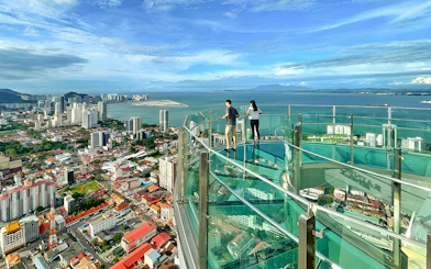 Couple enjoying city and sea view from The Top, Penang observation deck.