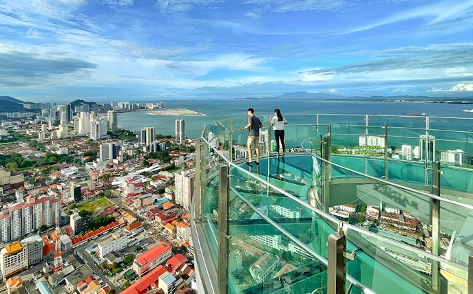 Couple enjoying city and sea view from The Top, Penang observation deck.