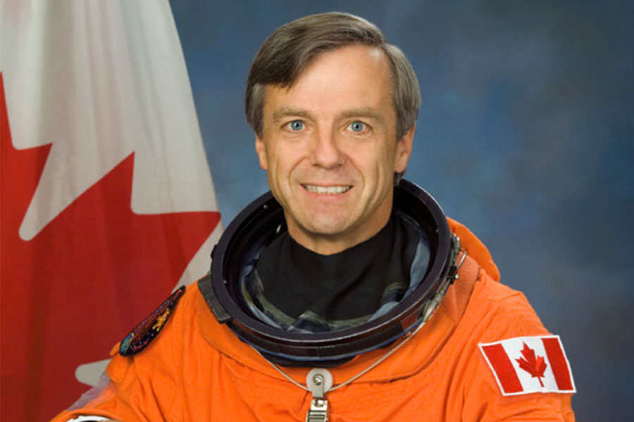 Astronaut Bob Thirsk in space suit with Canadian flag patch.