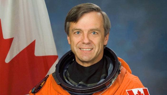 Astronaut Bob Thirsk in space suit with Canadian flag patch.