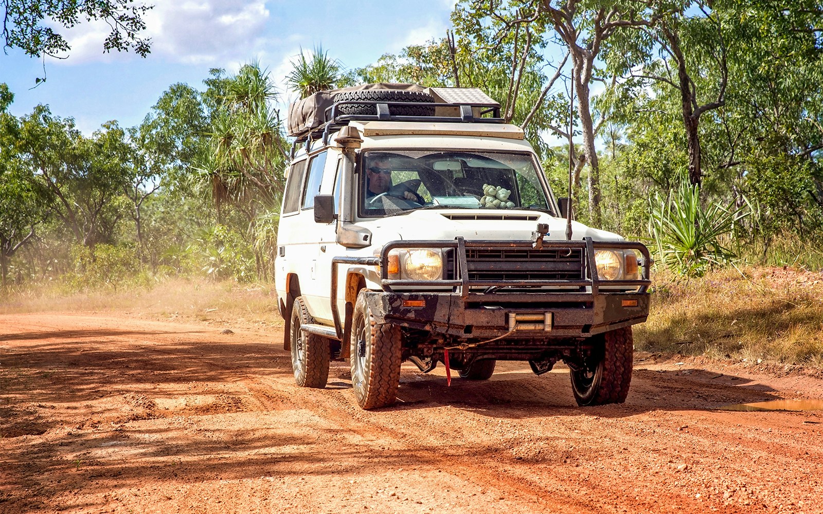 4WD vehicle driving on a dirt road through a forest on Moreton Island.