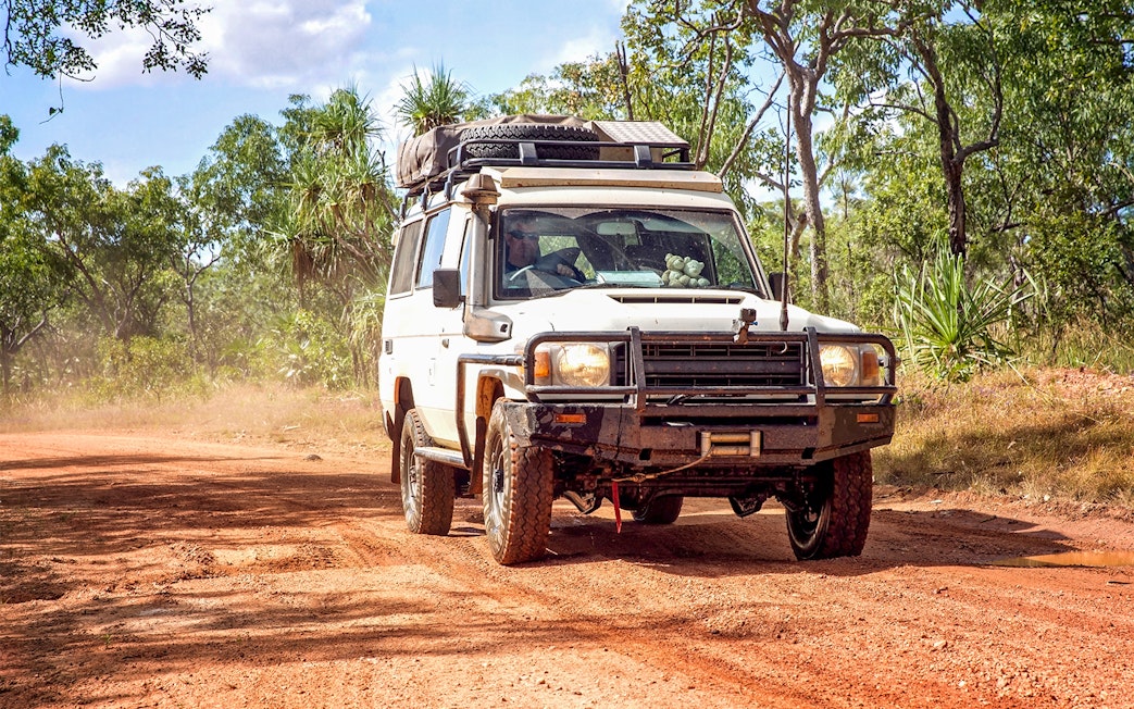 4WD vehicle driving on a dirt road through a forest on Moreton Island.