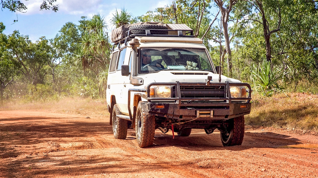 4WD vehicle driving on a dirt road through a forest on Moreton Island.