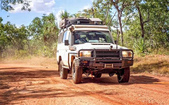 4WD vehicle driving on a dirt road through a forest on Moreton Island.