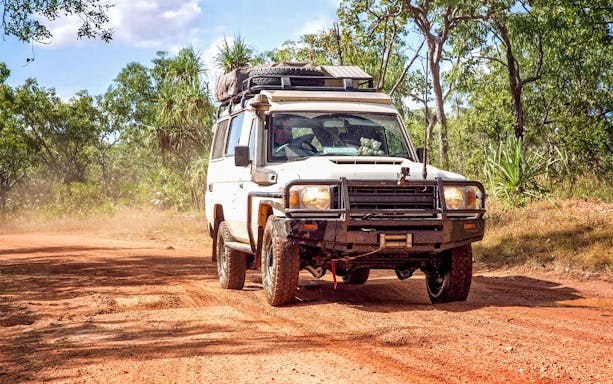 4WD vehicle driving on a dirt road through a forest on Moreton Island.