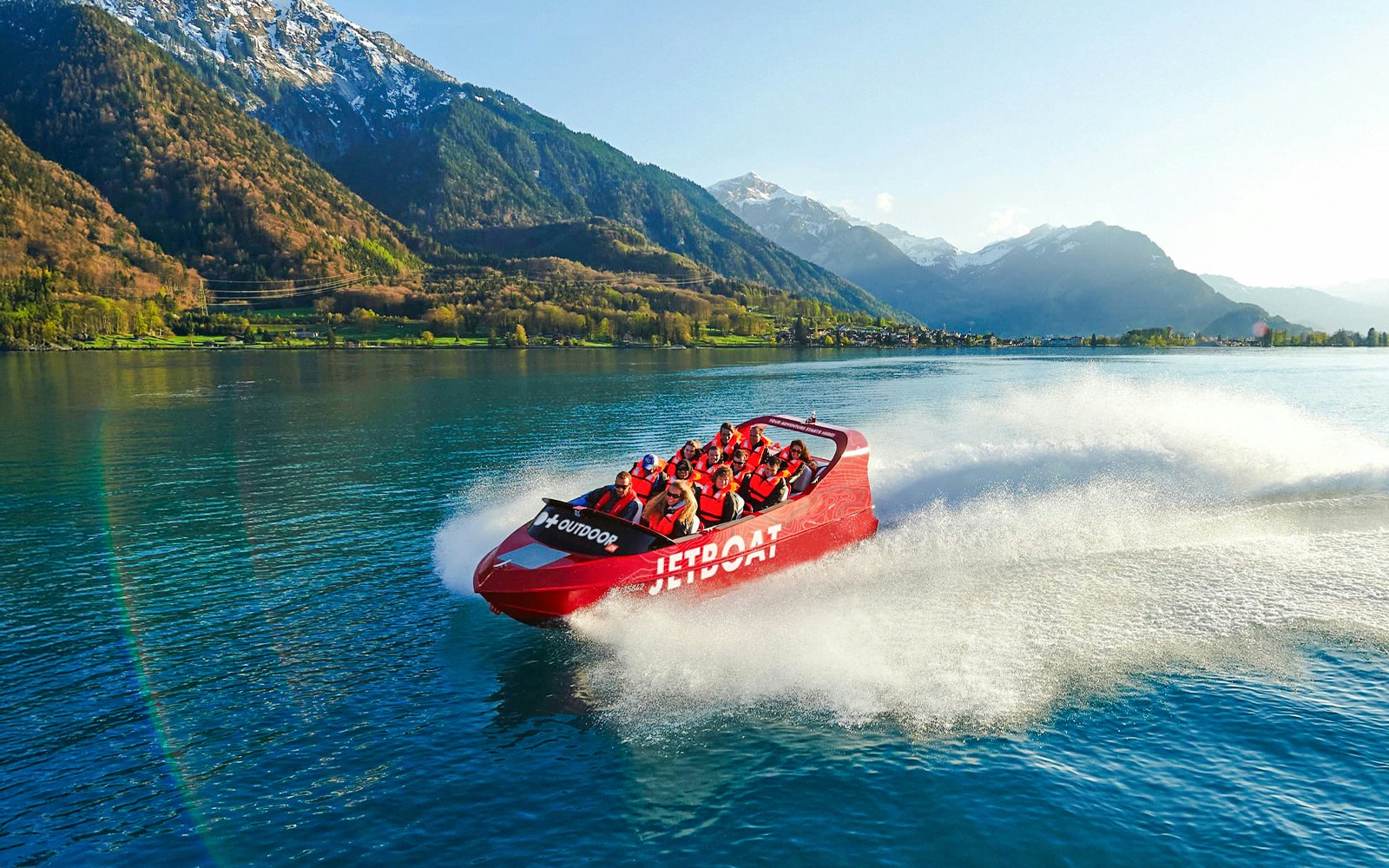 Jetboat speeding across Lake Brienz with passengers, surrounded by mountains.