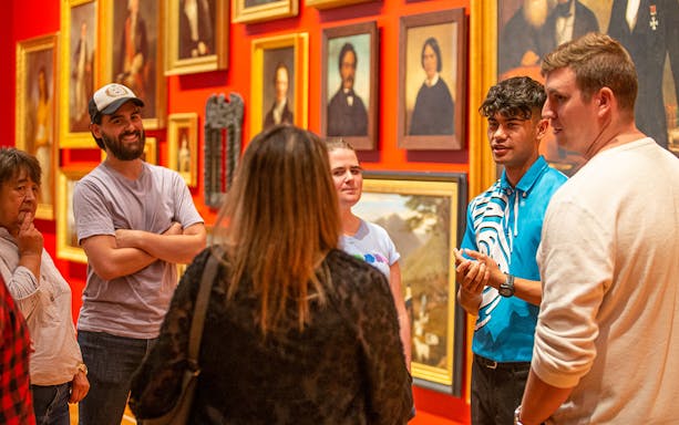 Group tour at Gallipoli Exhibition, Te Papa Tongarewa Museum, with guide discussing paintings.