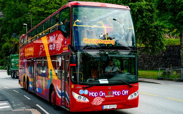 Bergen city sightseeing double-decker bus on a tree-lined street.