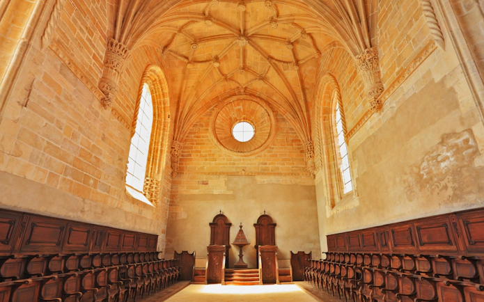 Chapel interior with vaulted ceiling and rows of oak chairs.